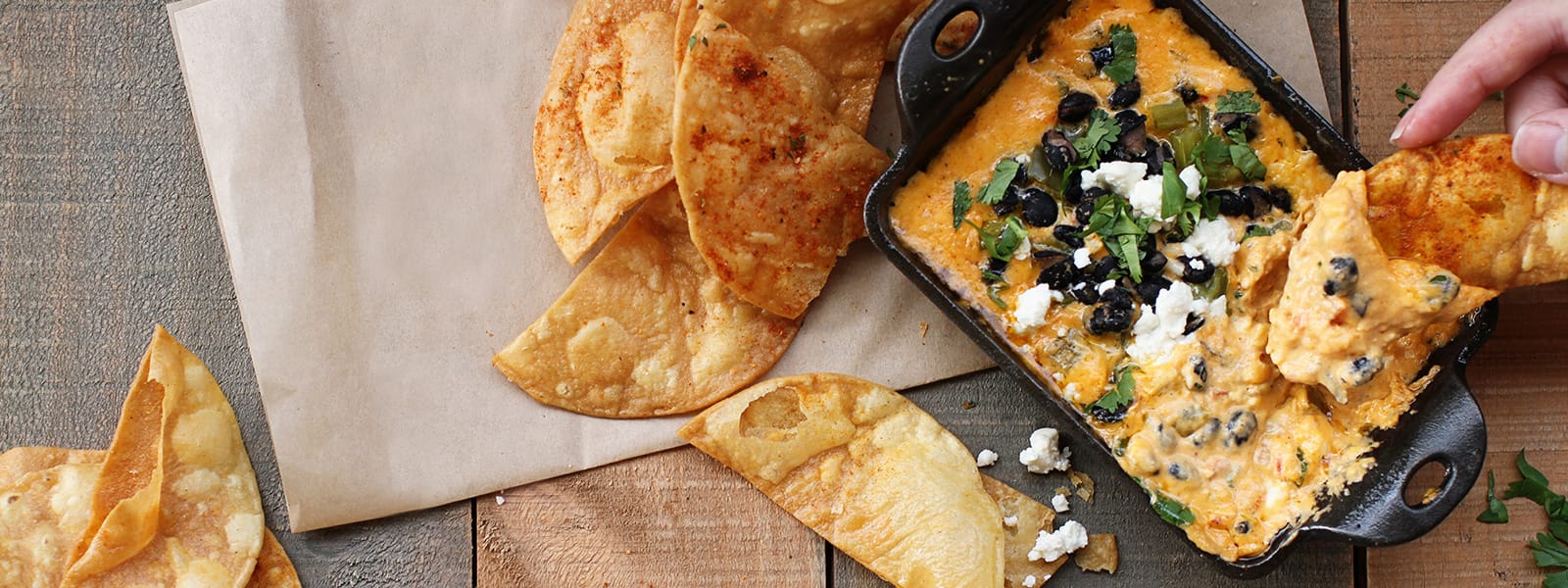 Chips being dipped into a cheese dip