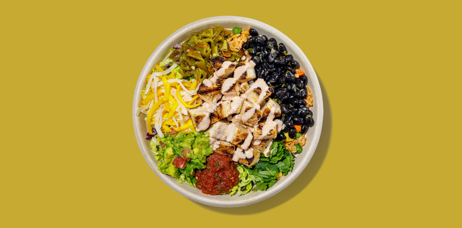 New Roadtrip Bowl called Blackened Chicken Bowl served with bed of rice, chicken breast, cabbage, guacamole, black beans, hatch chiles, jack + cheddar, salsa, corn, cilantro, tapatío crema alt tag